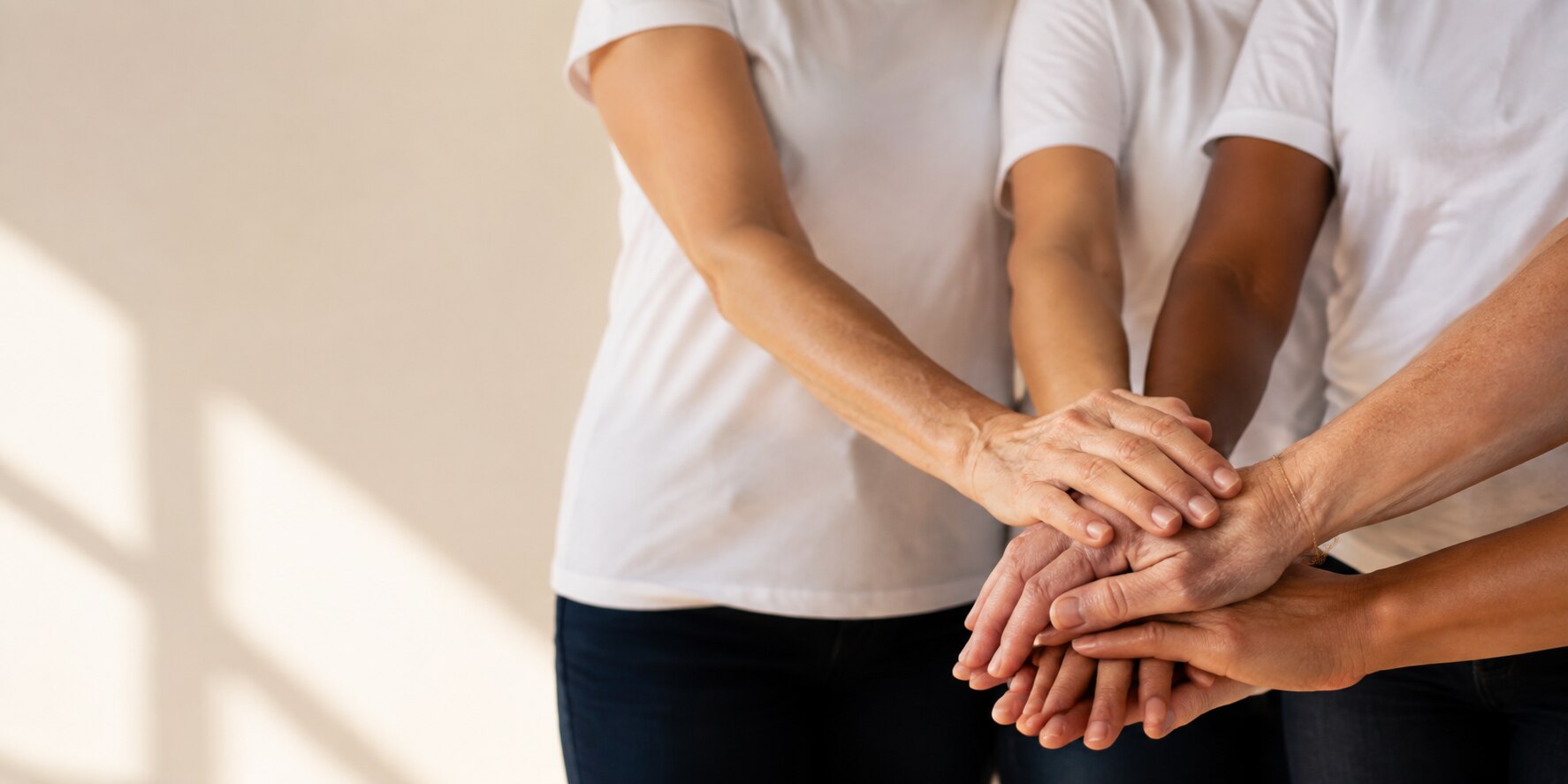 Diverse women placing their hands together in support